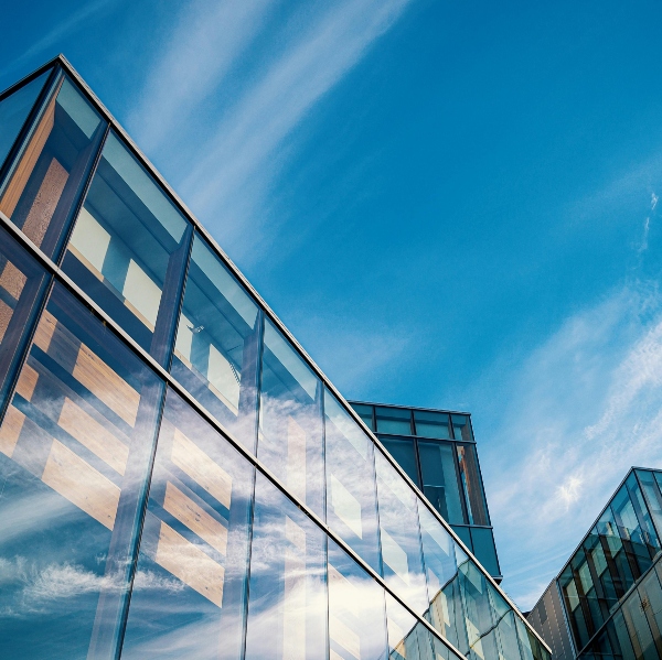 Contemporary commercial property with glass exterior reflecting clouds and sky